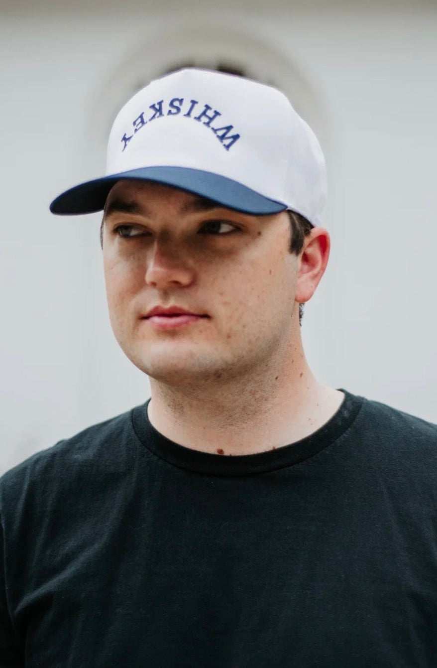 Person wearing a white cap with 'WHISKY' text against a plain background