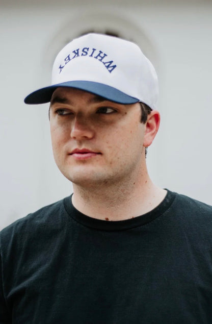 Person wearing a white cap with 'WHISKY' text against a plain background