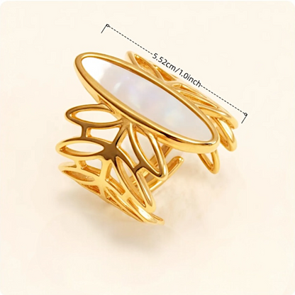 Gold ring with leaf-like design and measurements on a beige background