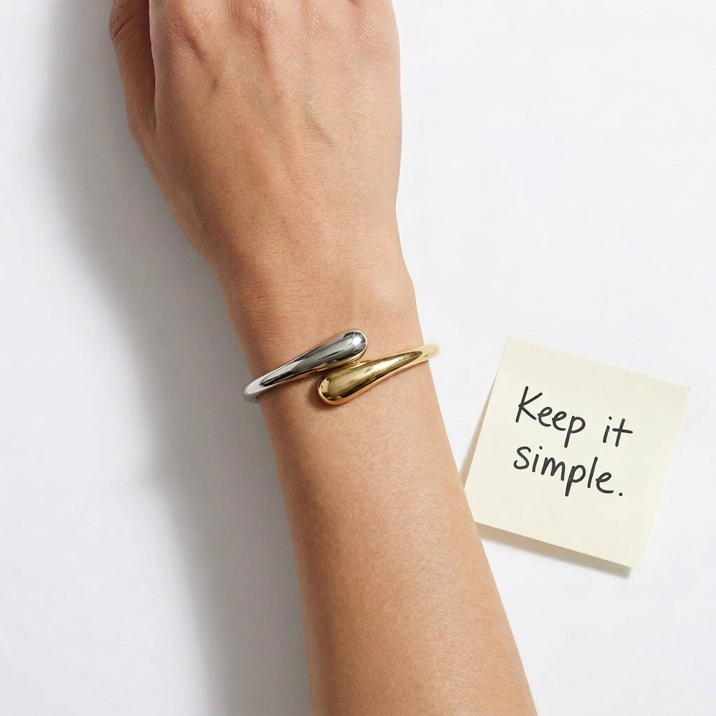 Gold bracelet on a wrist with a sticky note saying 'Keep it simple' on a white background