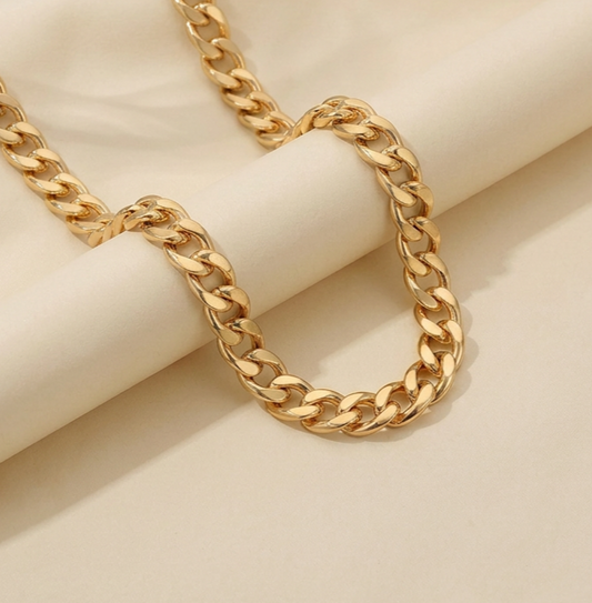Gold chain necklace on a beige background