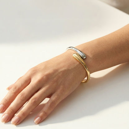 Gold and silver bracelet on a person's wrist against a light background