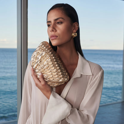 Woman holding a gold clutch with ocean view
