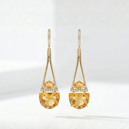 Gold earrings with yellow gemstones on a white background