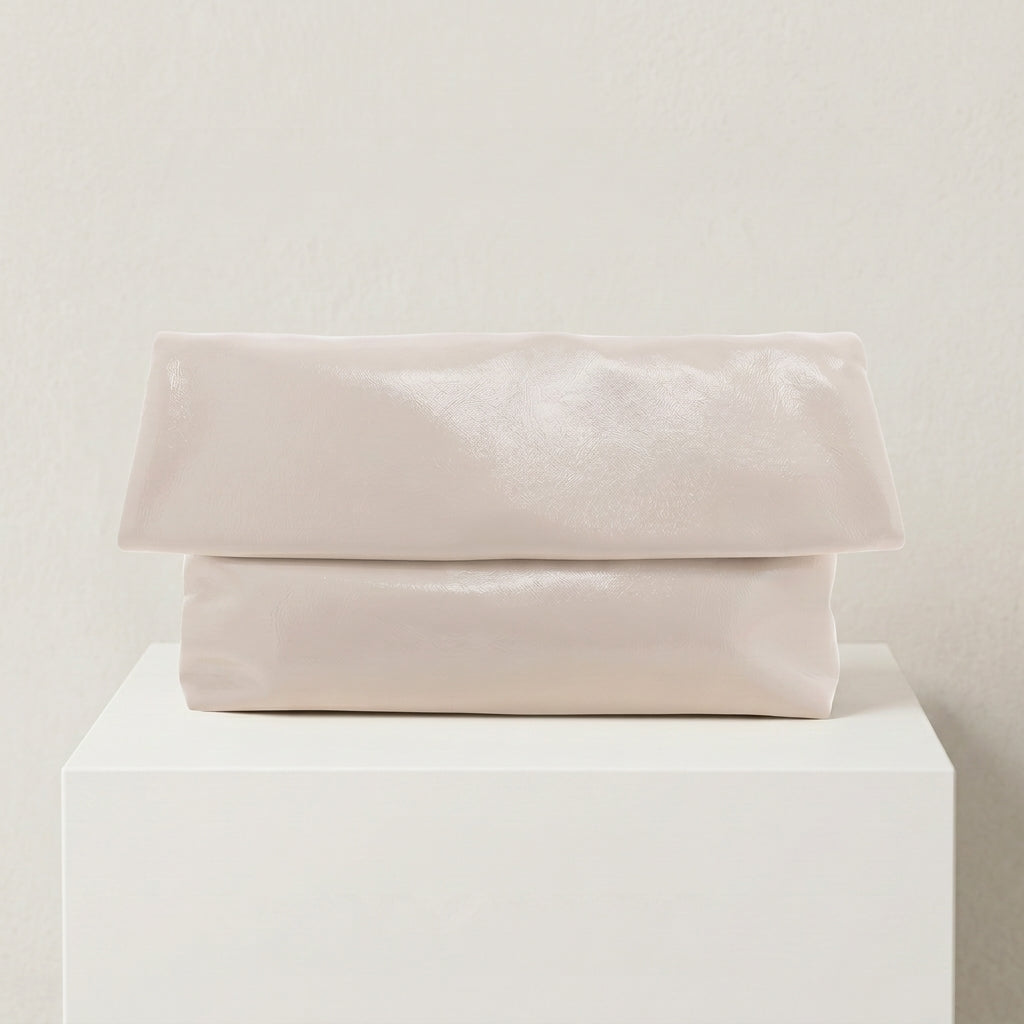 Folded light pink fabric on a white pedestal against a beige background
