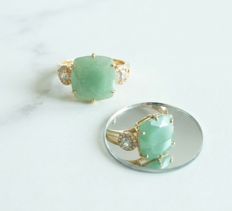 Gold ring with a green gemstone on a white background