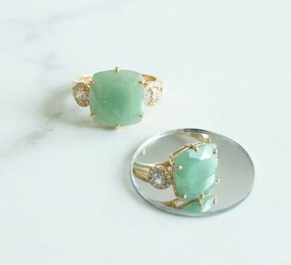 Gold ring with a green gemstone on a white background