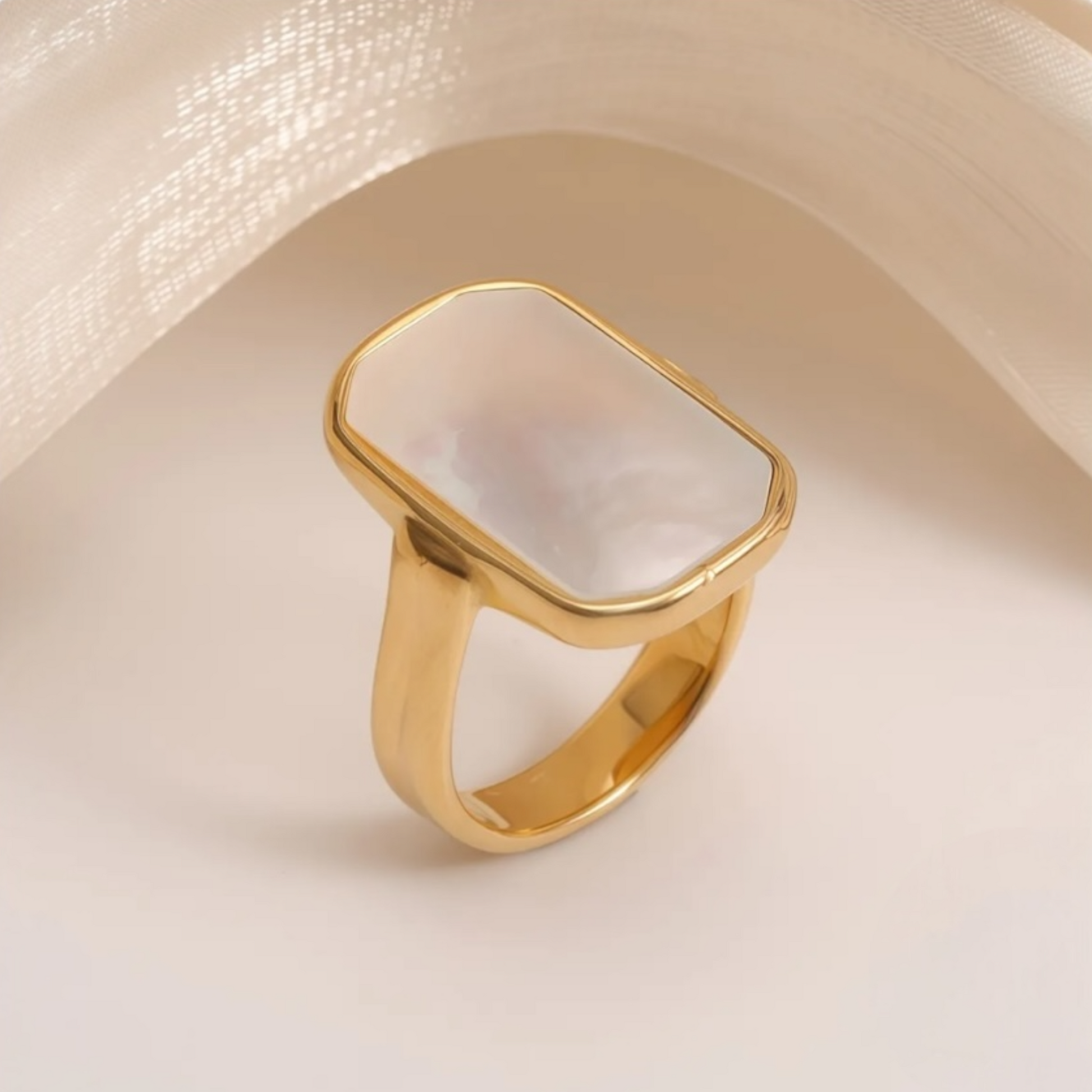 Gold ring with a white stone on a beige background