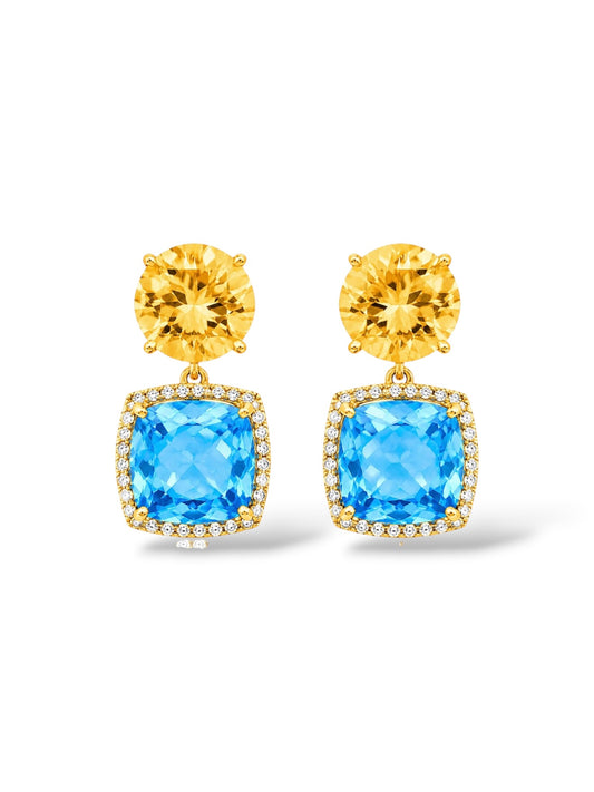 A pair of gold drop earrings featuring a round yellow gemstone on top of a square blue gemstone surrounded by small pavé-set clear stones, shown on a white background.