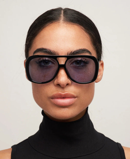 Person wearing large black sunglasses with a plain background