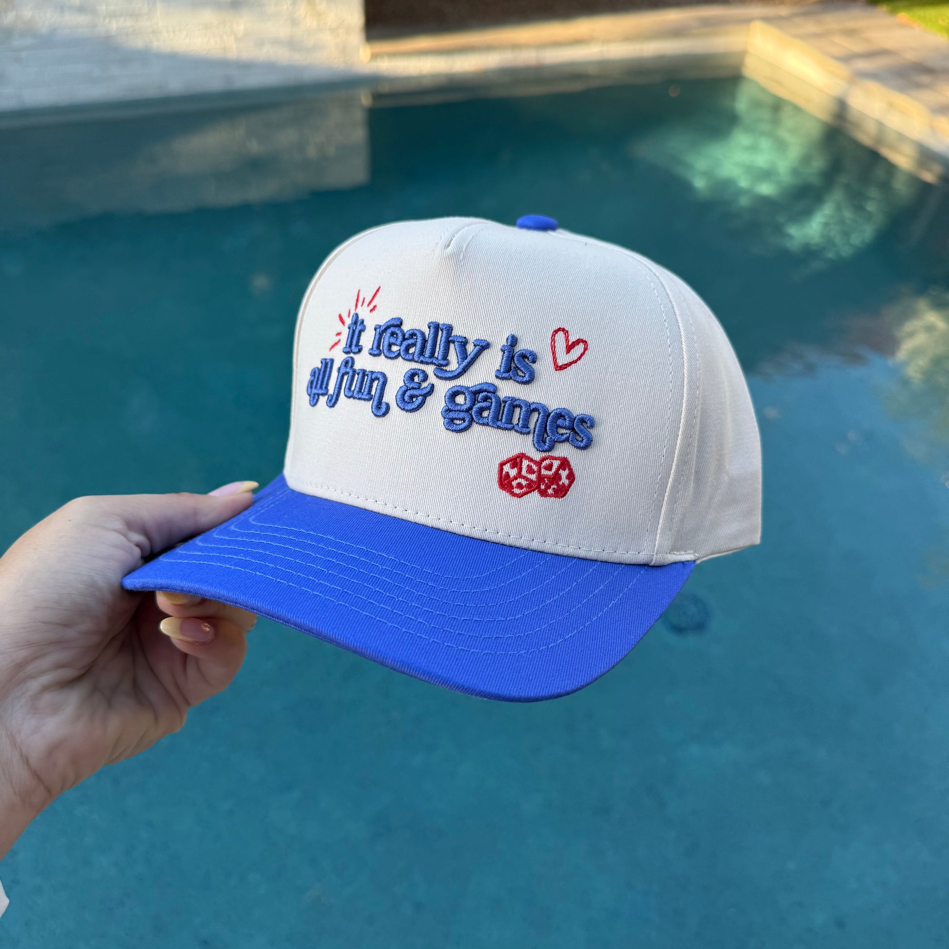 White and blue cap with text held by a hand by a pool