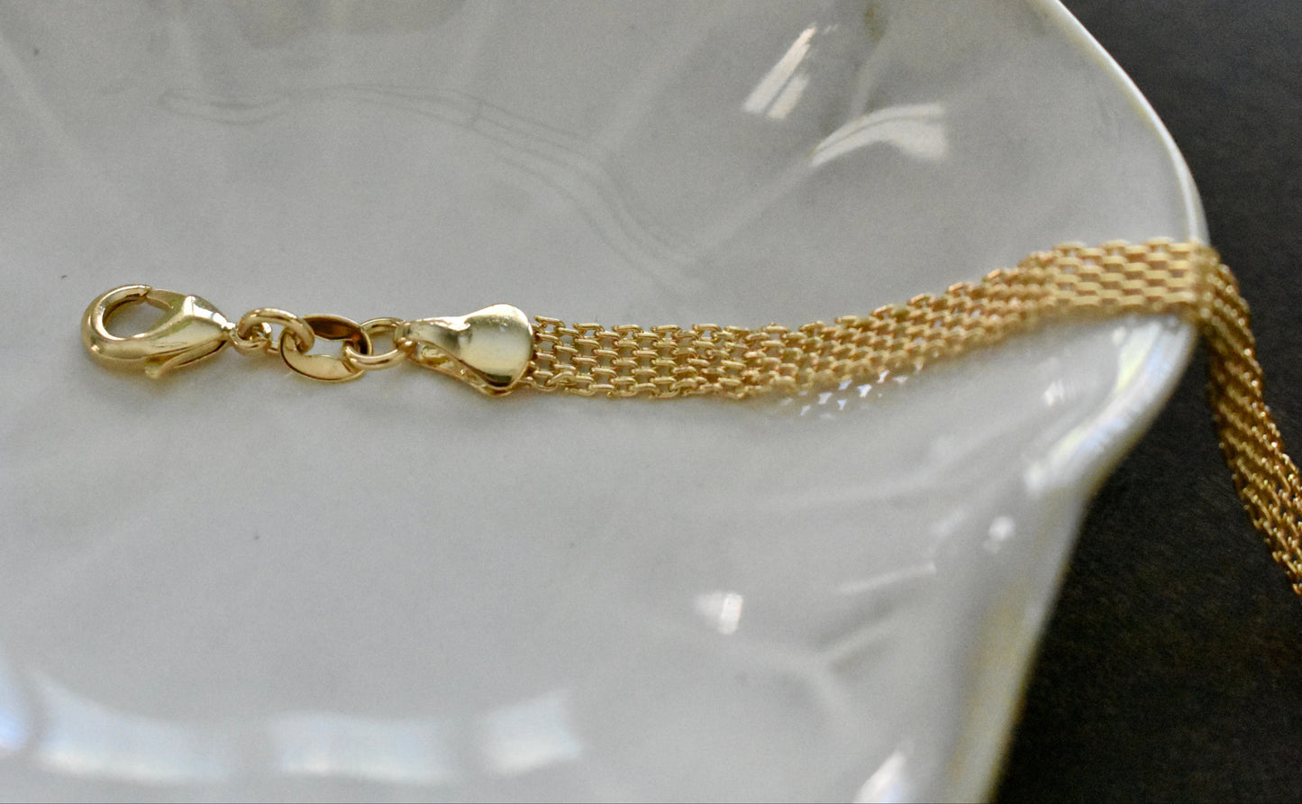 Gold bracelet with clasp on a white dish