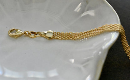 Gold bracelet with clasp on a white dish