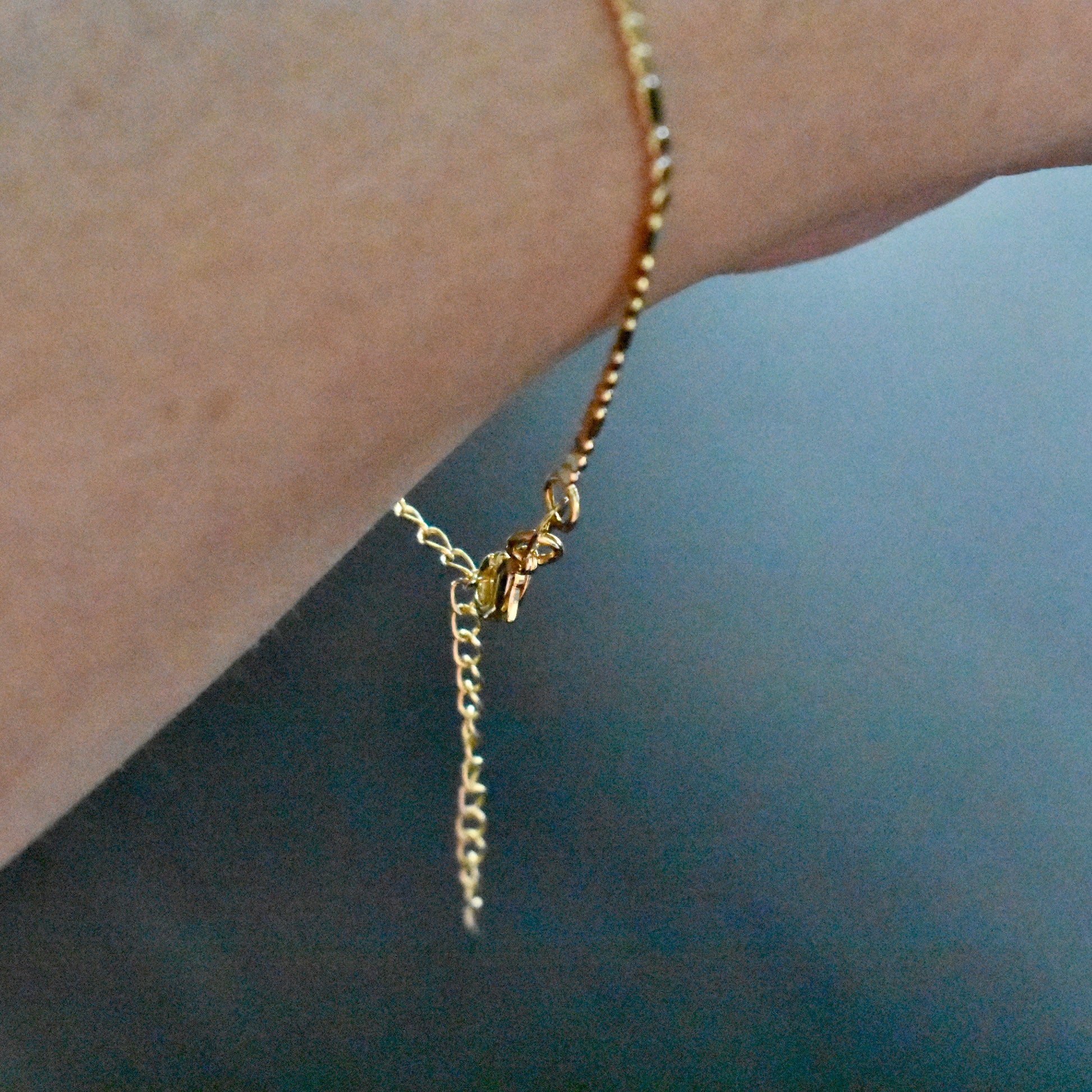 Gold bracelet on a wrist against a dark background