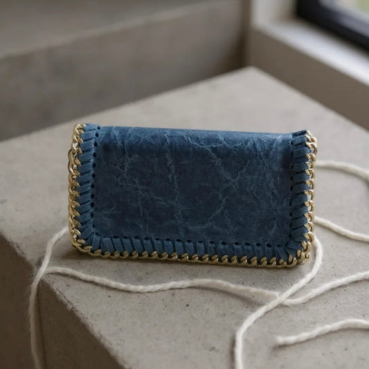 Blue textured clutch bag with gold trim on a concrete surface