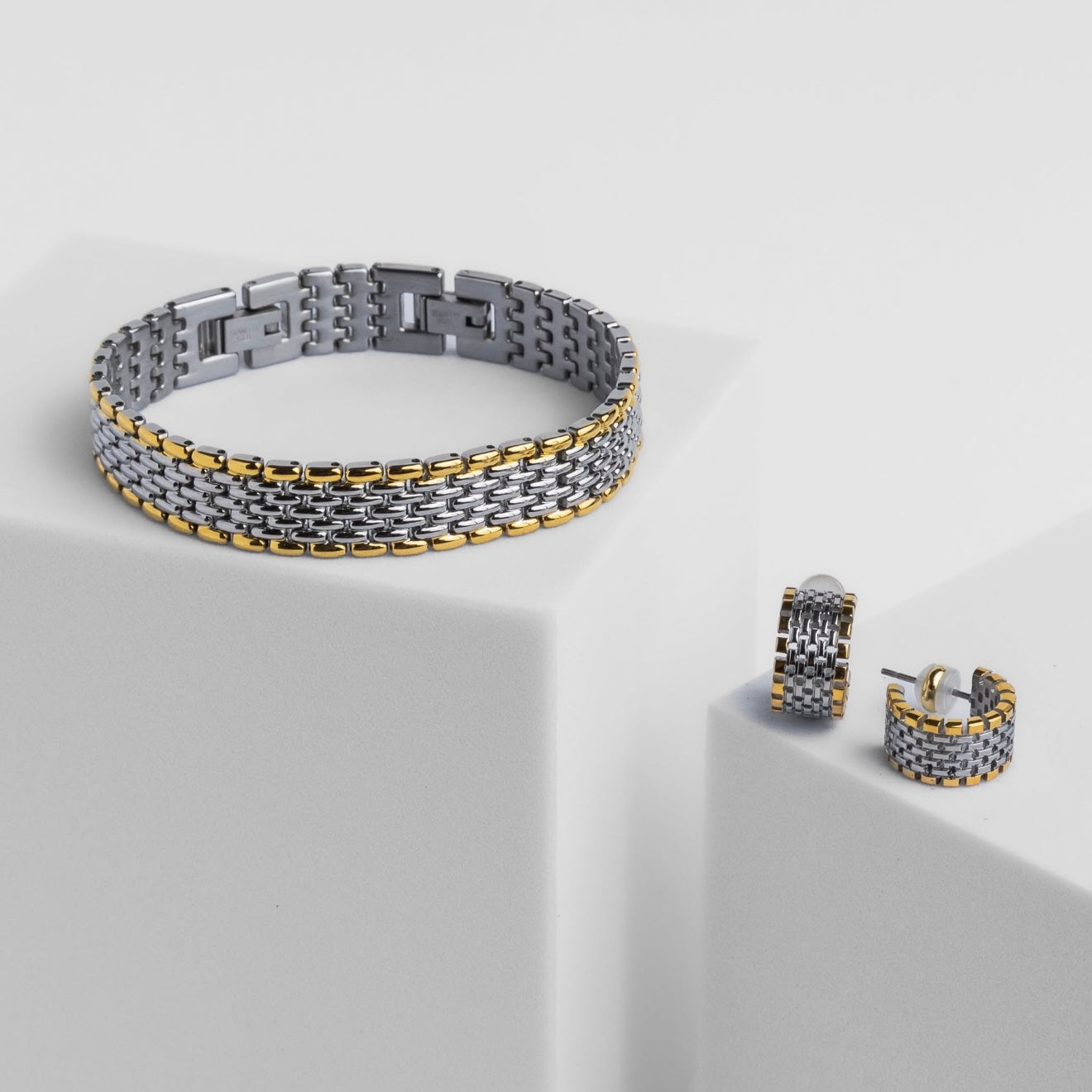 Two-tone bracelet and earrings on a light gray background