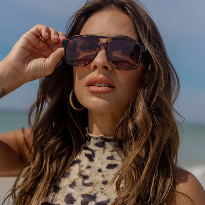 Woman wearing sunglasses with a beach background