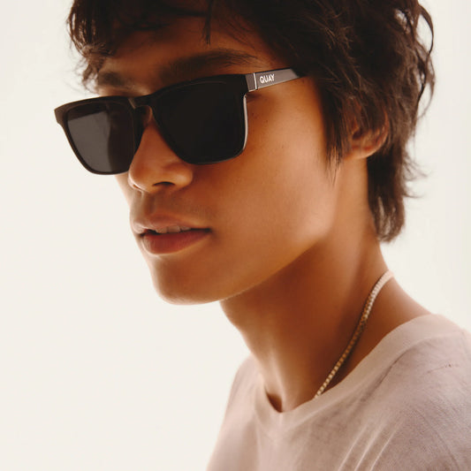 Person wearing black sunglasses with a neutral background