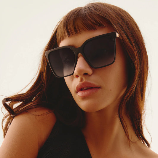 Woman wearing dark sunglasses with a neutral background