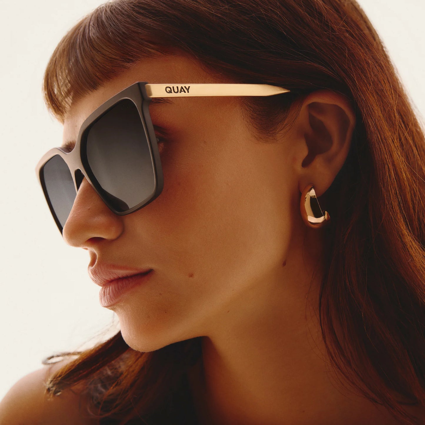 Woman wearing Quay sunglasses with a blurred background
