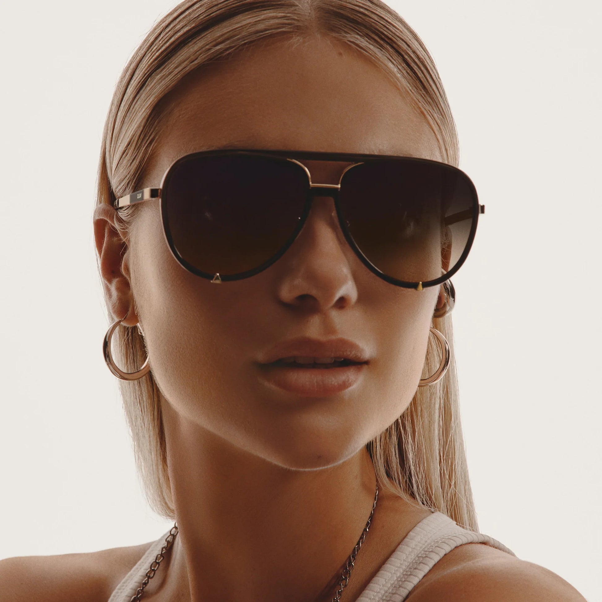 Close-up of a woman wearing dark sunglasses with a neutral background