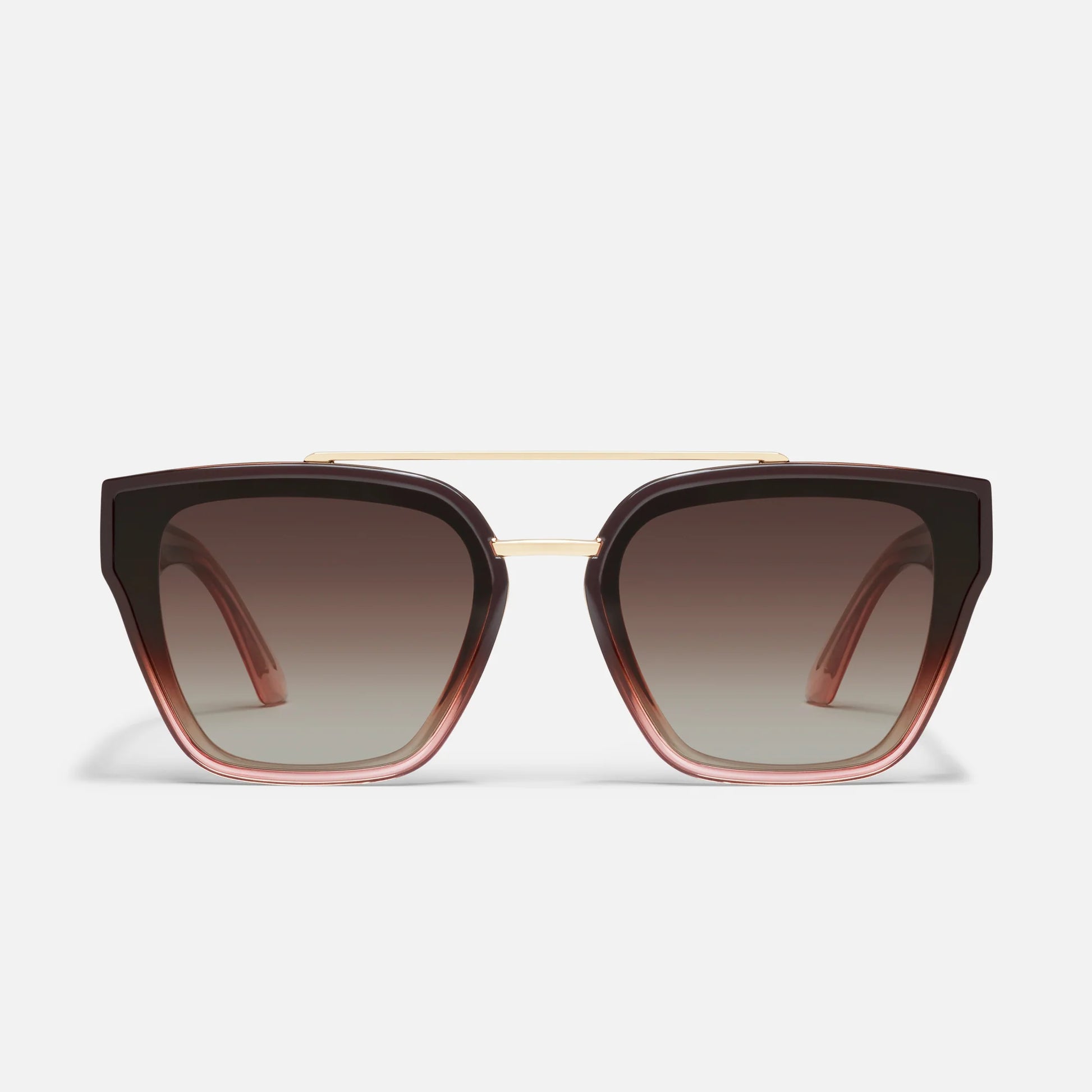 Sunglasses with brown gradient lenses and gold frame on a light gray background