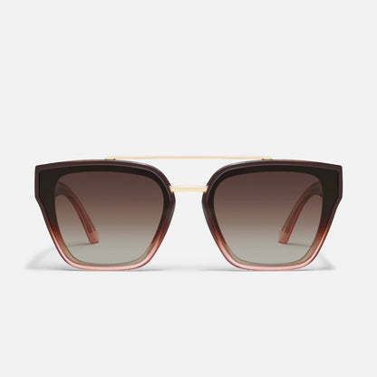 Sunglasses with brown gradient lenses and gold frame on a light gray background
