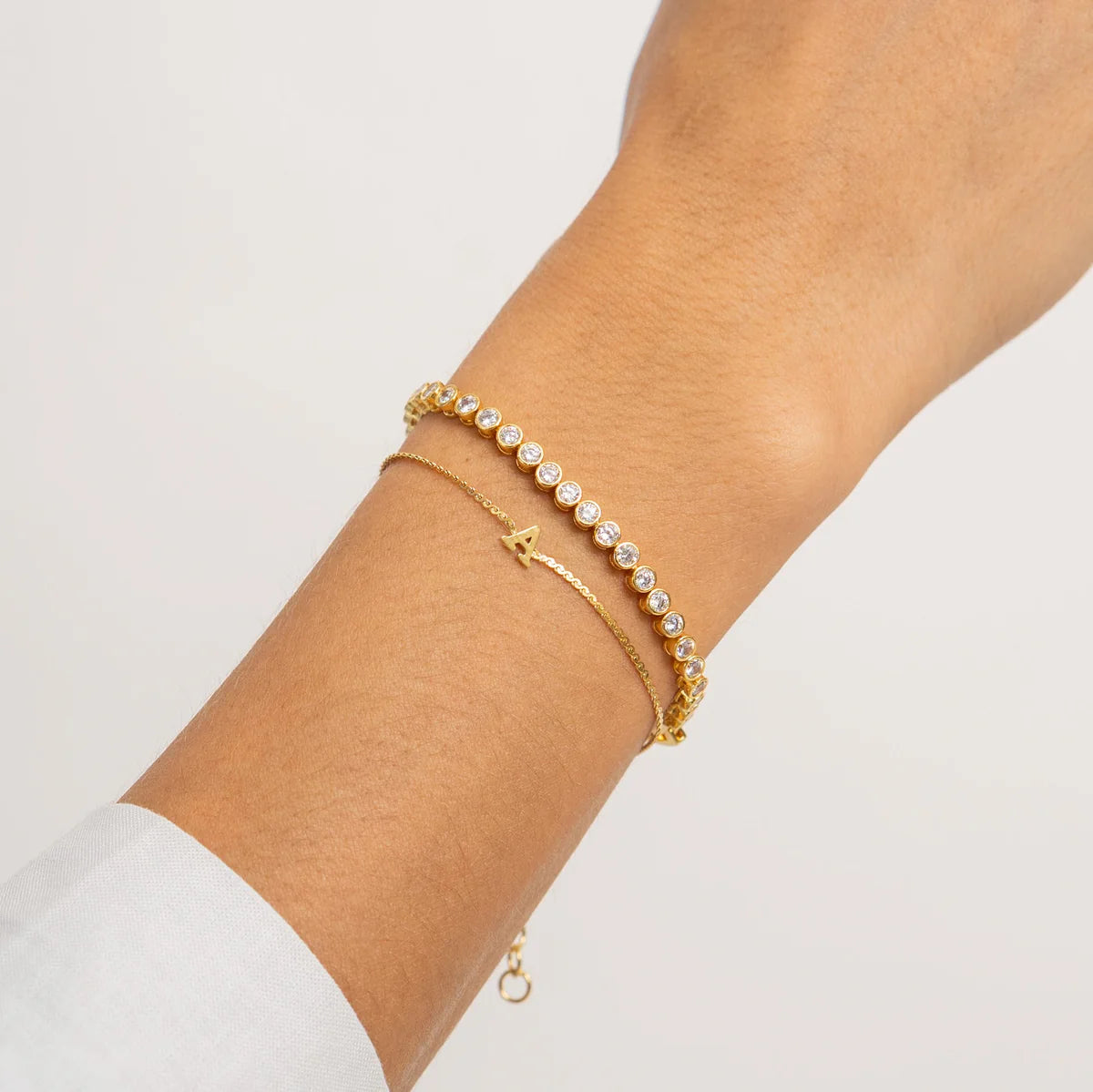 Gold bracelet with small pearls on a wrist against a light background