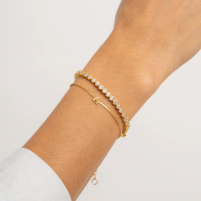 Gold bracelet with small pearls on a wrist against a light background