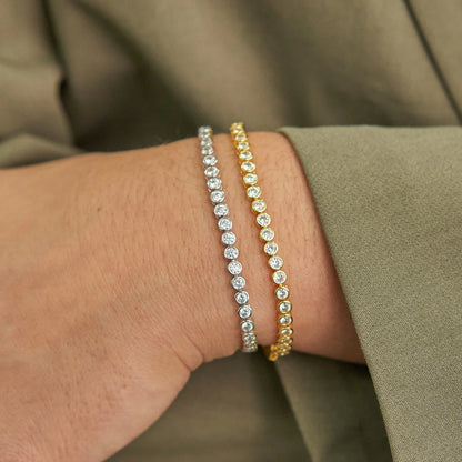 Two diamond bracelets on a person's wrist with a blurred background