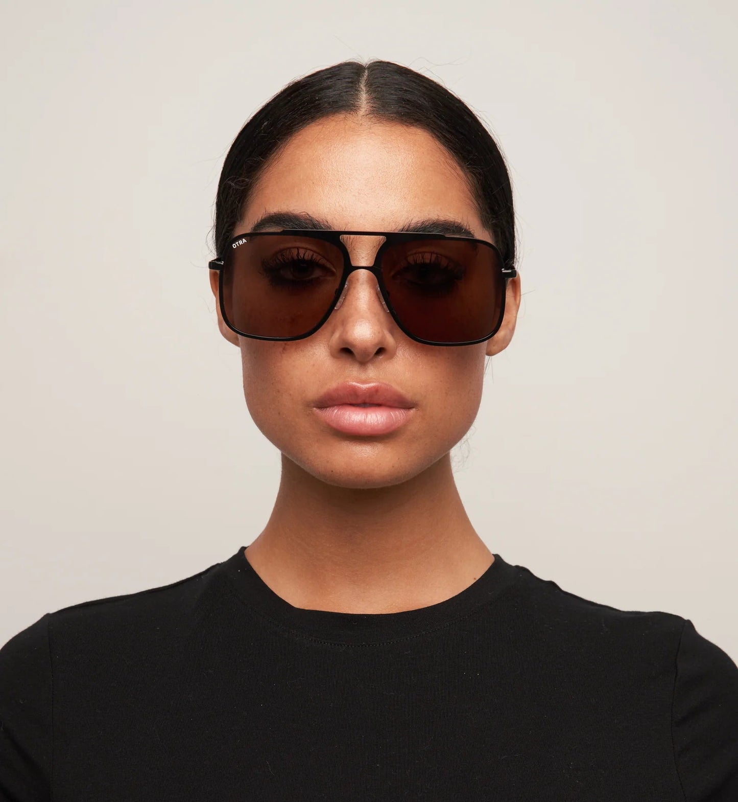Person wearing dark sunglasses and a black shirt against a neutral background