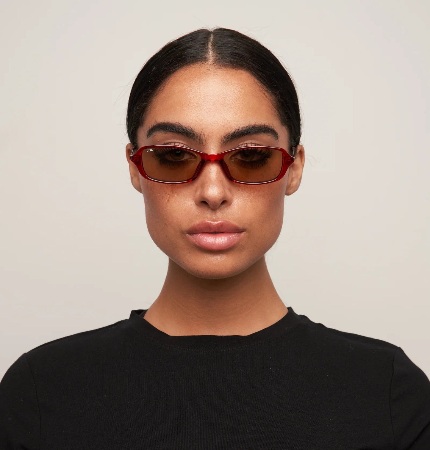 Person wearing sunglasses and a black shirt against a plain background