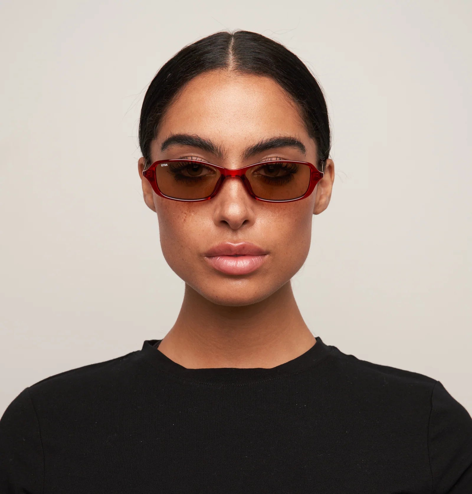 Person wearing sunglasses and a black shirt against a plain background