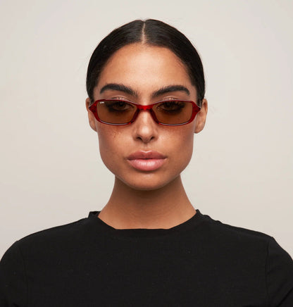 Person wearing sunglasses and a black shirt against a plain background