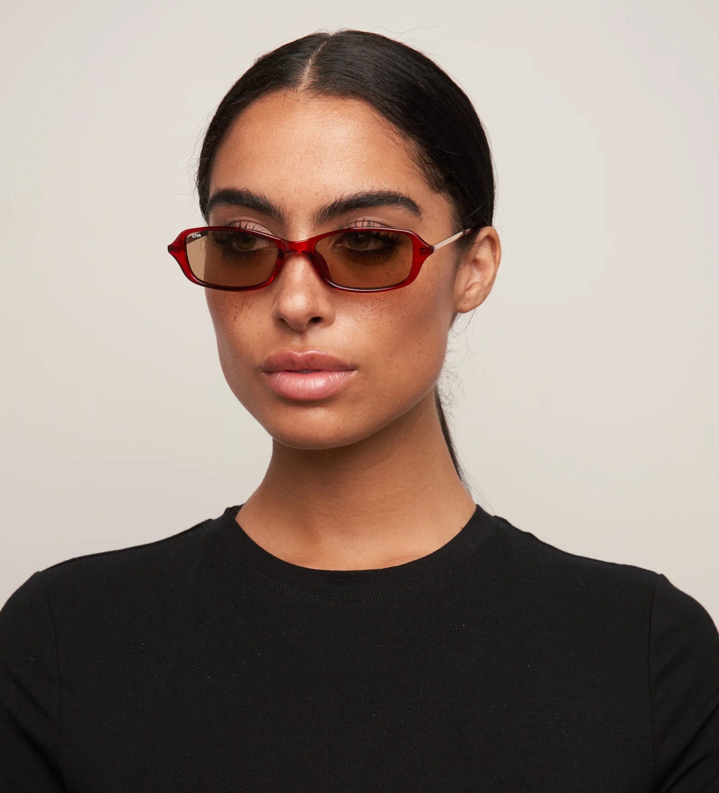 Person wearing red sunglasses and a black shirt against a plain background