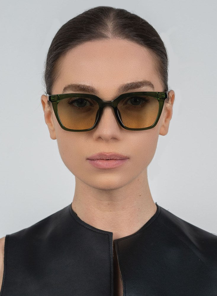 Woman wearing green sunglasses against a gray background