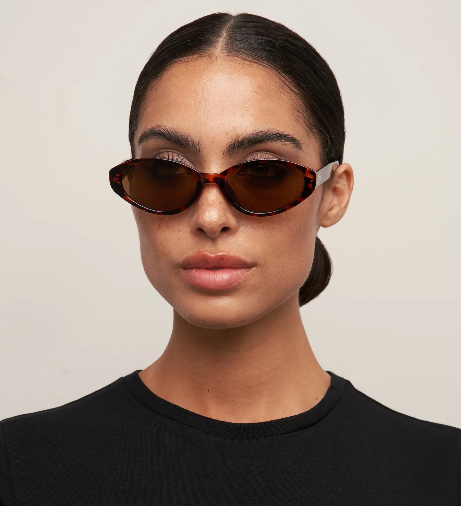 Woman wearing brown sunglasses against a plain background