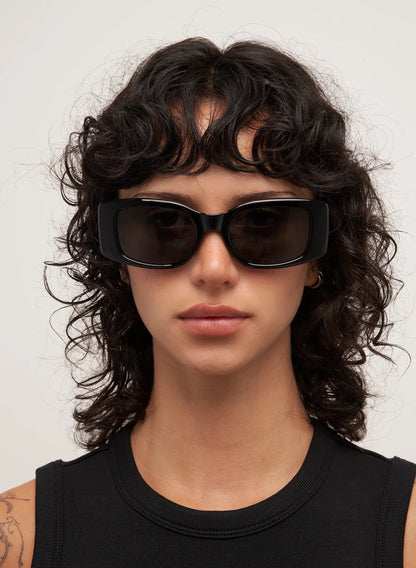 Person wearing black sunglasses with a neutral background