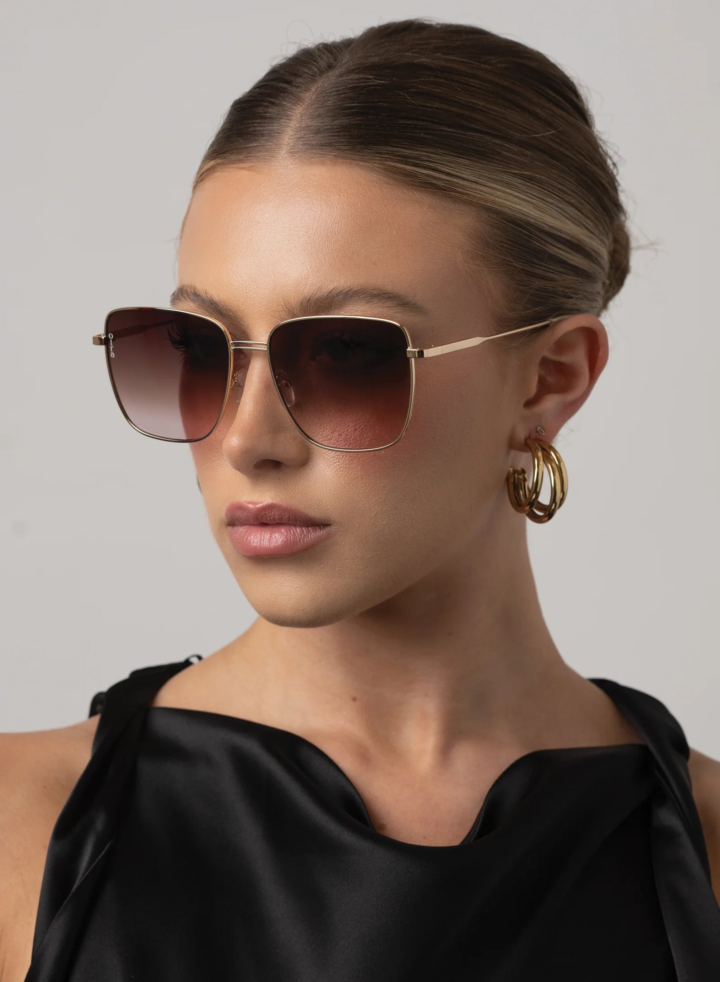 Woman wearing sunglasses and a black top against a neutral background