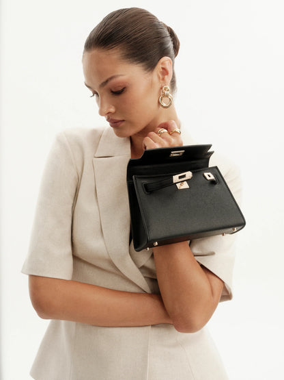 Woman holding a black handbag against a white background