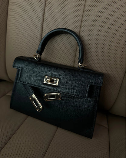 Black handbag with silver hardware on a beige car seat