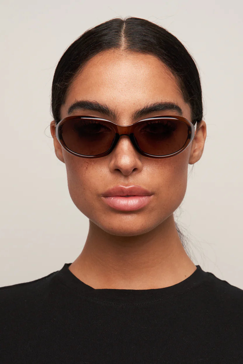 Woman wearing brown sunglasses against a plain background