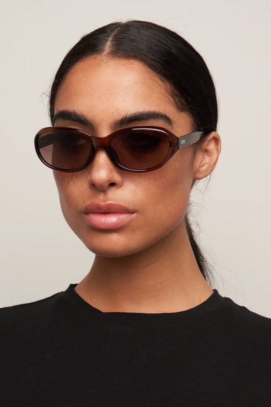 Woman wearing brown sunglasses against a plain background