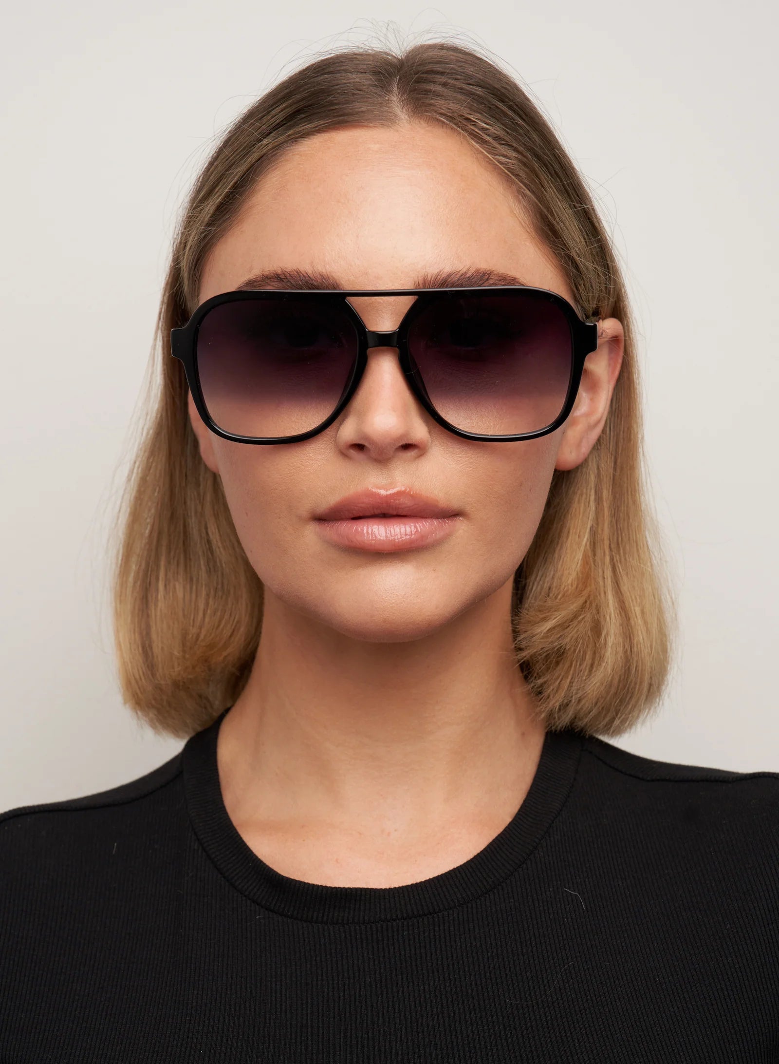 Woman wearing large sunglasses with a plain background