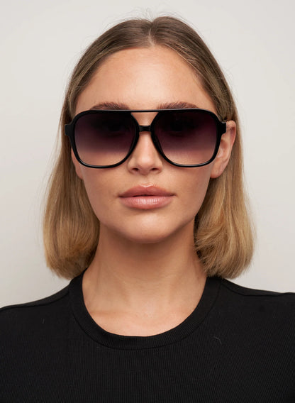 Woman wearing large sunglasses with a plain background