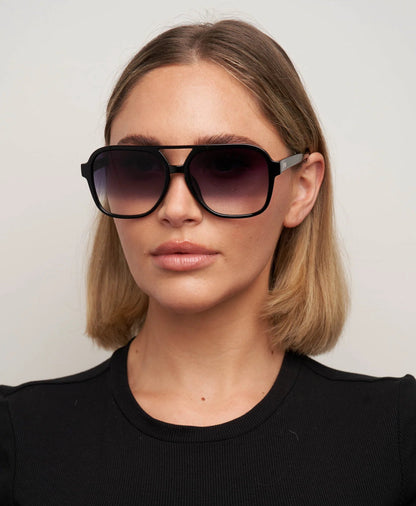 Woman wearing large sunglasses against a plain background
