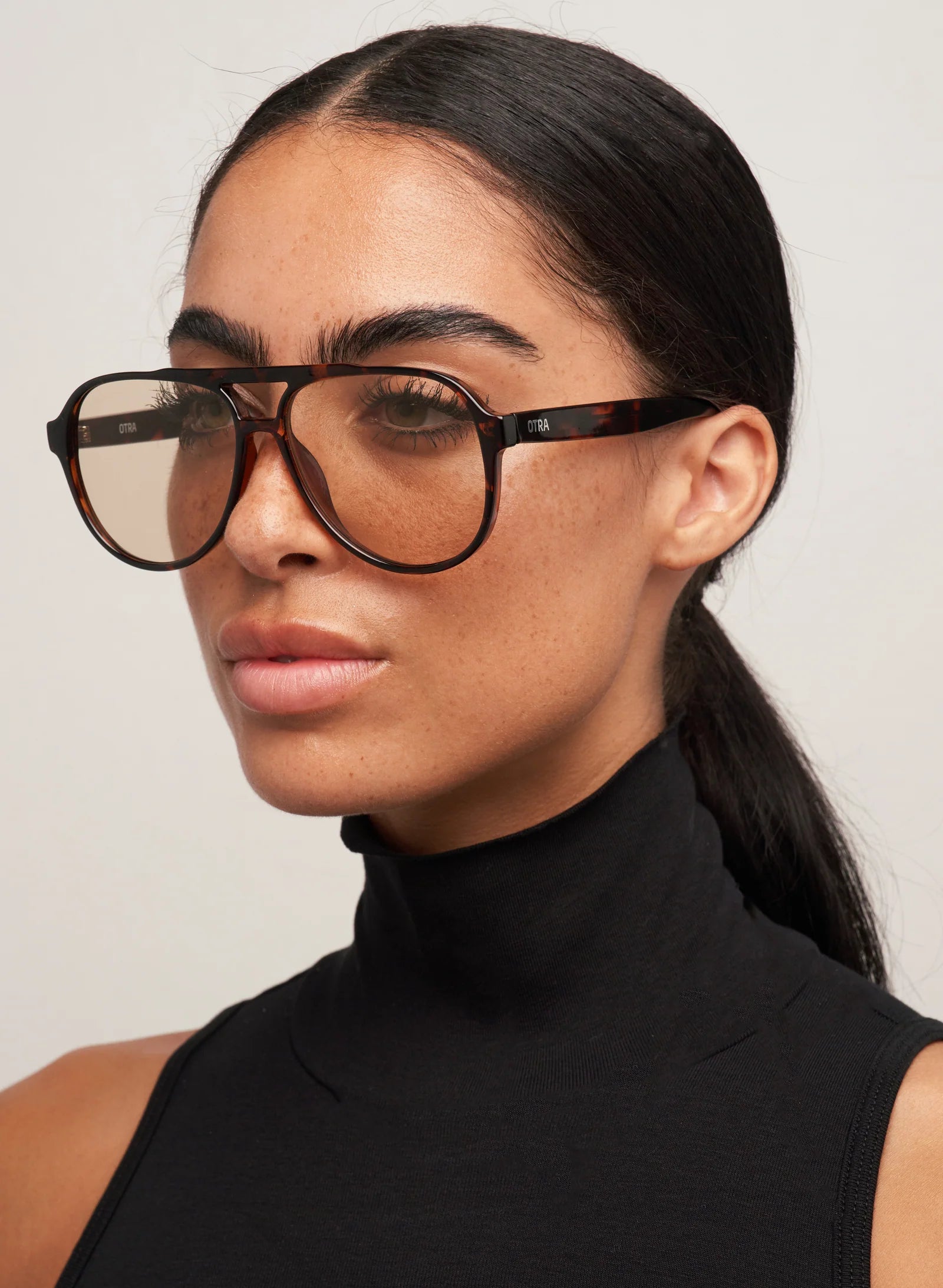 Woman wearing large sunglasses with a plain background