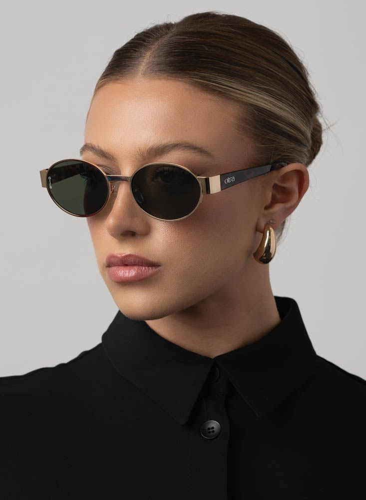 Woman wearing round sunglasses with a plain background