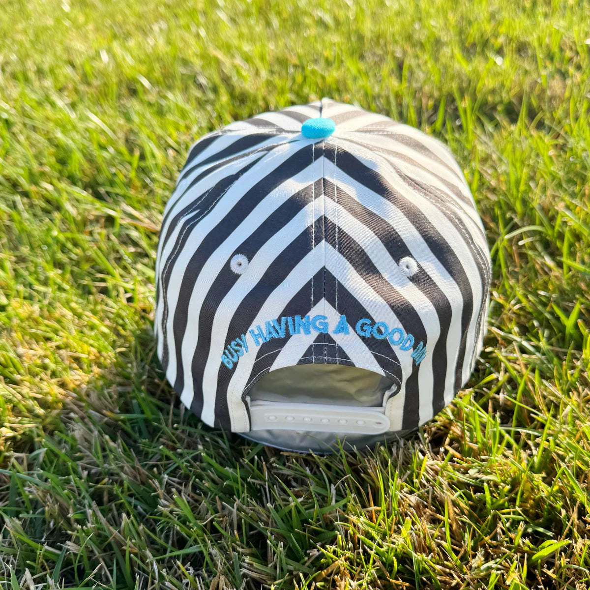Black and white striped cap with blue text on grass