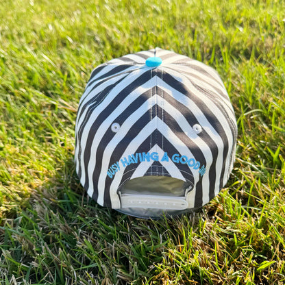 Black and white striped cap with blue text on grass